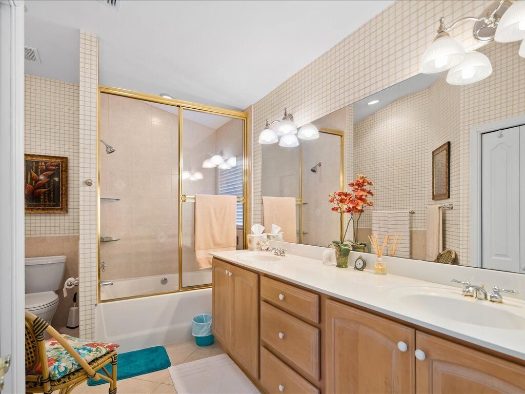 A bathroom with a large mirror, two sinks, a bathtub, and a shower.