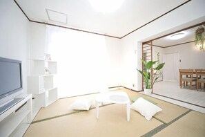 A room with tatami flooring, a television, a white sofa, a small table, and a potted plant. - Higashiomi Large House (Higashiomi)