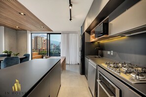 A modern kitchen with a gas stove, built-in microwave, and a large window overlooking a cityscape. - Morph 1602 - Luxurious Retreat in Poblado/Jacuzzi/Air Conditioning (Medellín)