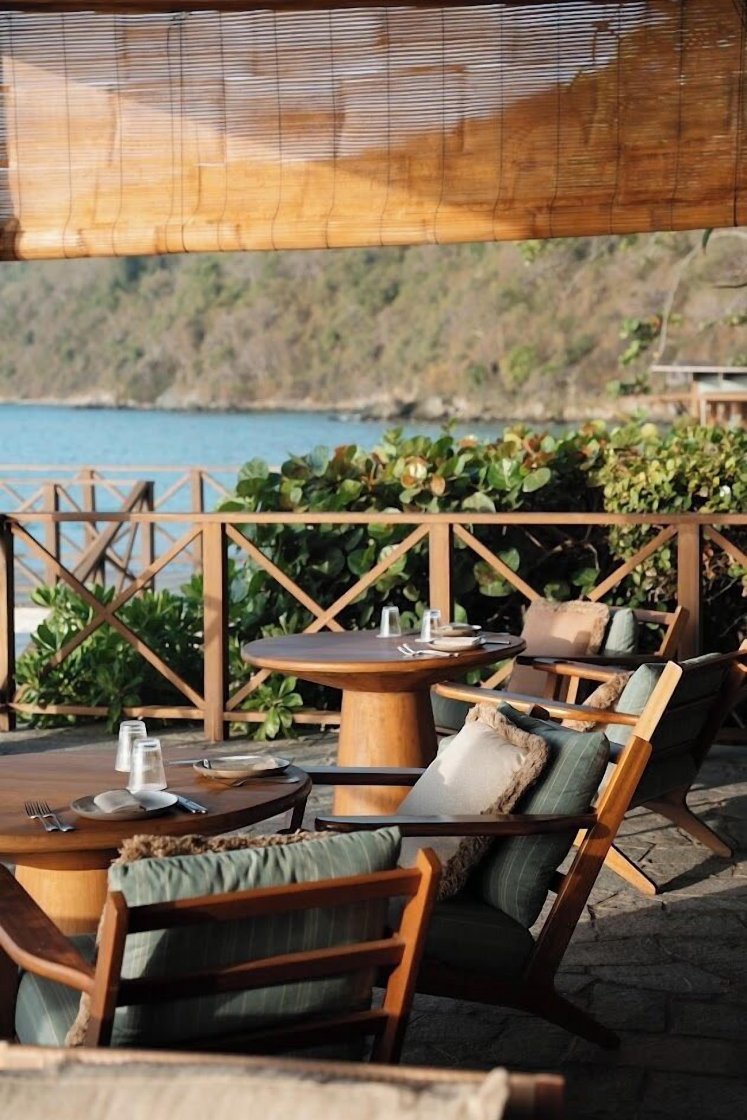 An outdoor seating area with wooden furniture and a view of the sea.