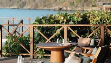 An outdoor seating area with wooden furniture and a view of the sea.