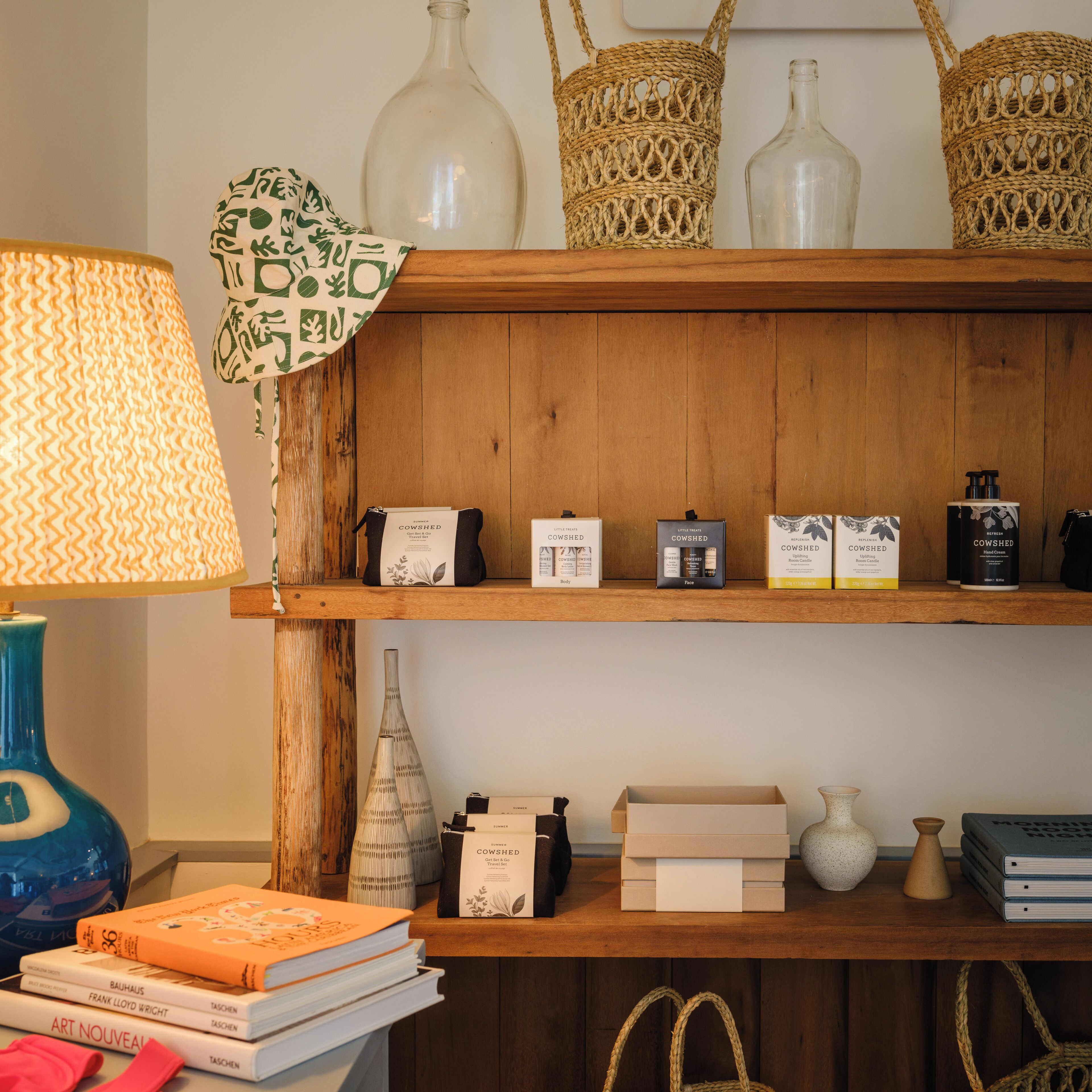 A wooden shelf with books, a lamp, and various items including a vase and a woven basket.