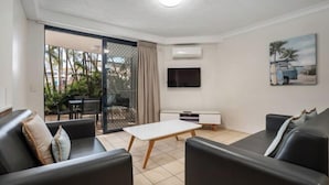 A modern living room with a sofa, a coffee table, a TV, and a painting on the wall. - Turtle Beach Resort (Mermaid Beach)