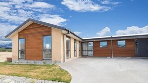 Ein modernes, zweistöckiges Haus mit Satteldach, großen Fenstern und einer Betonauffahrt.