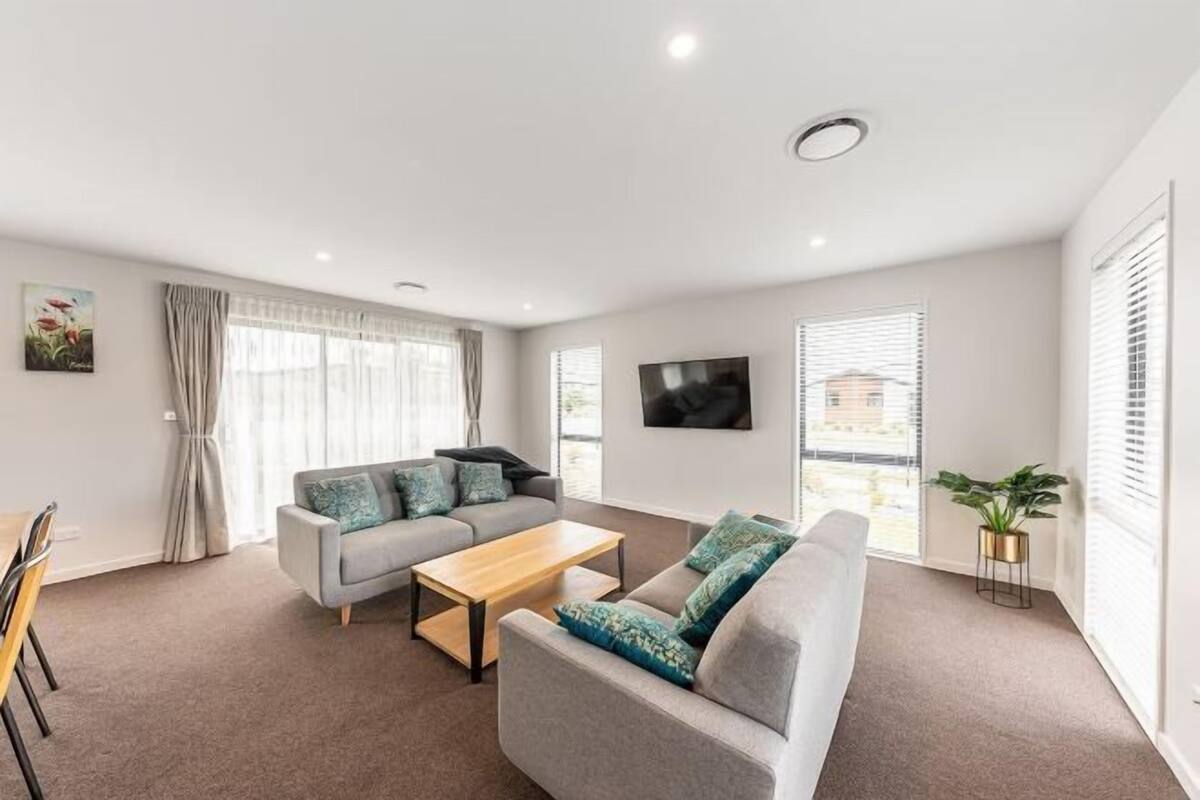 A modern living room with a sofa, coffee table, and curtains.