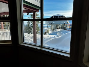 A window view of a snowy landscape with a ski lift and trees. - Amazing ski in/out, steps from Silver Woods w/ hot tub and pet friendly too! (Silver Star Mountain)