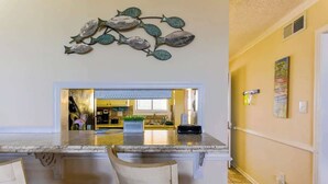 Una cocina con encimera de mármol, un cuadro de peces y vistas al área de comedor.