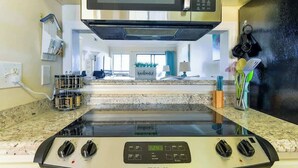 Una cocina con microondas, estufa y vista a un salón.