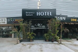 A hotel entrance with a sign reading 'Regency Sunset Hotel' and potted plants in front. - RedDoorz Premium @ Regency Sunset Hotel (Angeles City)