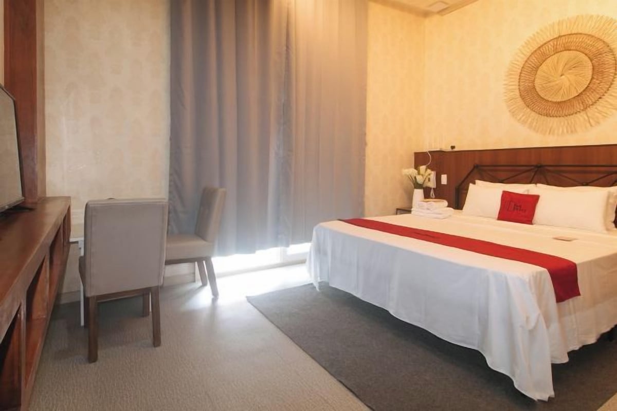 Une chambre d’hôtel comprenant un lit, un bureau, une chaise et un grand élément de décoration circulaire fixé au mur.