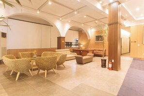A hotel lobby with a seating area, a reception desk, and a staircase. - RedDoorz Premium @ Regency Sunset Hotel (Angeles City)
