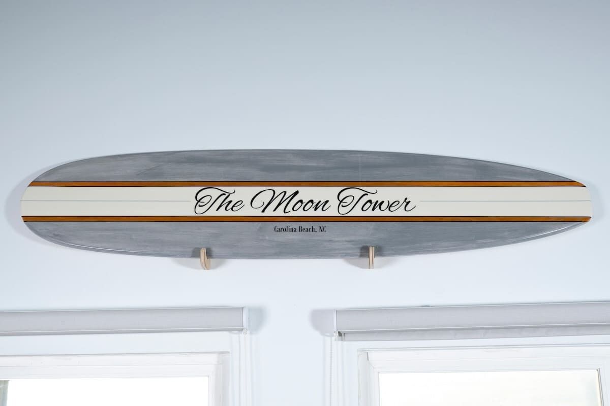 Et skilt med teksten 'The Moon Tower' og 'Carolina Beach, NC' på en væg.