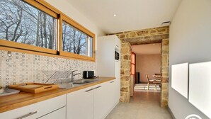 A modern kitchen with a wooden countertop, white cabinets, and a large window. - Le Tejtal 6pers - PLUMERGAT (PLUMERGAT)