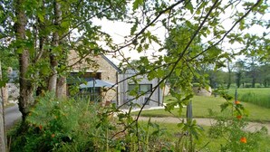 A stone building with a modern design, surrounded by lush greenery and a well-maintained lawn. - Le Tejtal 6pers - PLUMERGAT (PLUMERGAT)