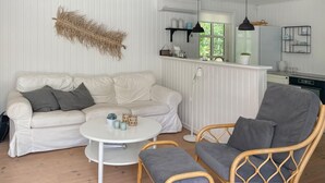 A cozy living room with a white sofa, a grey armchair, and a small round table. - Stunning home in Hals with WiFi (Hals)
