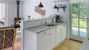 A kitchen with white cabinetry, a built-in stove, a sink, and a window with a view of greenery. - Stunning home in Hals with WiFi (Hals)
