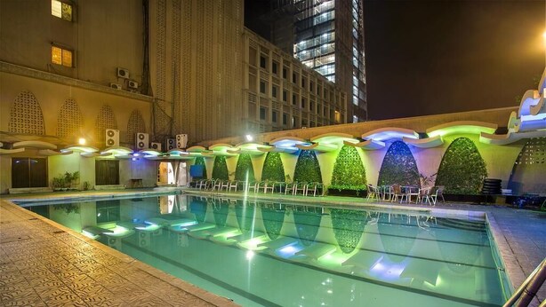 A swimming pool with a modern design, surrounded by a building with balconies and a patterned floor. - Agrabad Hotel (Chittagong)