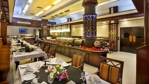 A restaurant with multiple tables, a buffet area, and decorative columns. - Agrabad Hotel (Chittagong)
