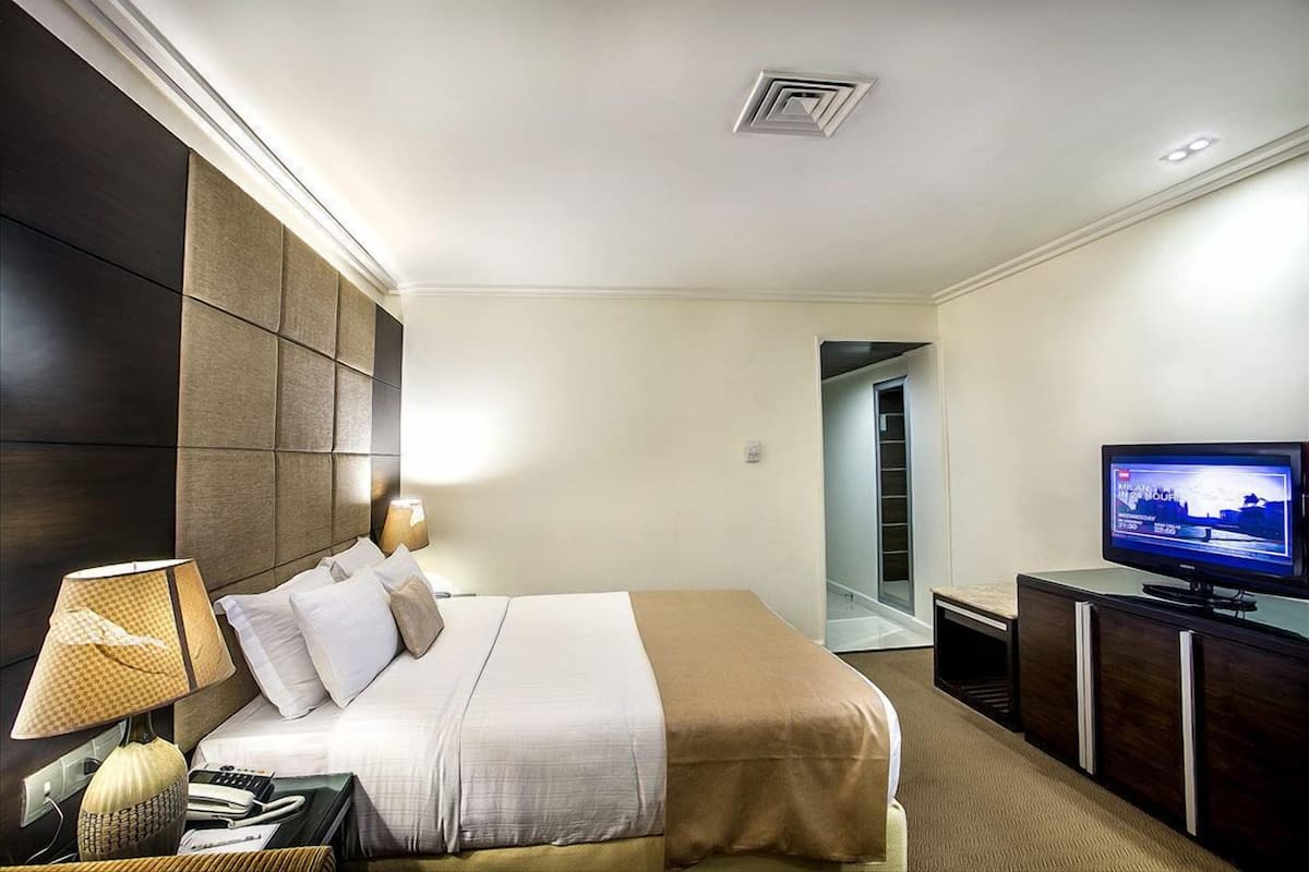 Ein Hotelzimmer mit einem Bett, einem Fernseher, einer Lampe, einem Telefon und einem Schreibtisch.