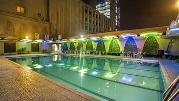 Une piscine au design moderne, entourée d’un bâtiment doté de balcons et d’un sol à motifs.