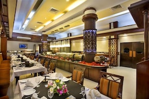 A restaurant with multiple tables, a buffet area, and decorative columns. - Agrabad Hotel (Chittagong)