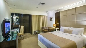 A hotel room with a bed, a desk with a computer, a chair, a sofa, and a TV. - Agrabad Hotel (Chittagong)