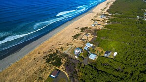 Oversigtsbillede af et kystområde med strand, huse og frodig vegetation.