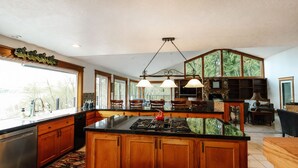 A spacious kitchen with a large island, wooden cabinets, and a stone backsplash. - Mayfield Lake Waterfront Escape (Mossyrock)