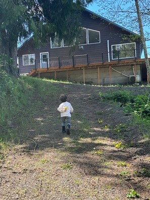 Un niño corre hacia una casa moderna con amplios ventanales y una terraza de madera.