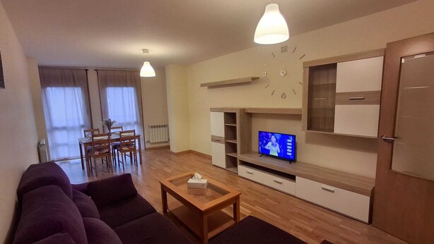 Un saló modern amb un conjunt de sofàs, una taula de centre, una televisió i prestatges de paret.