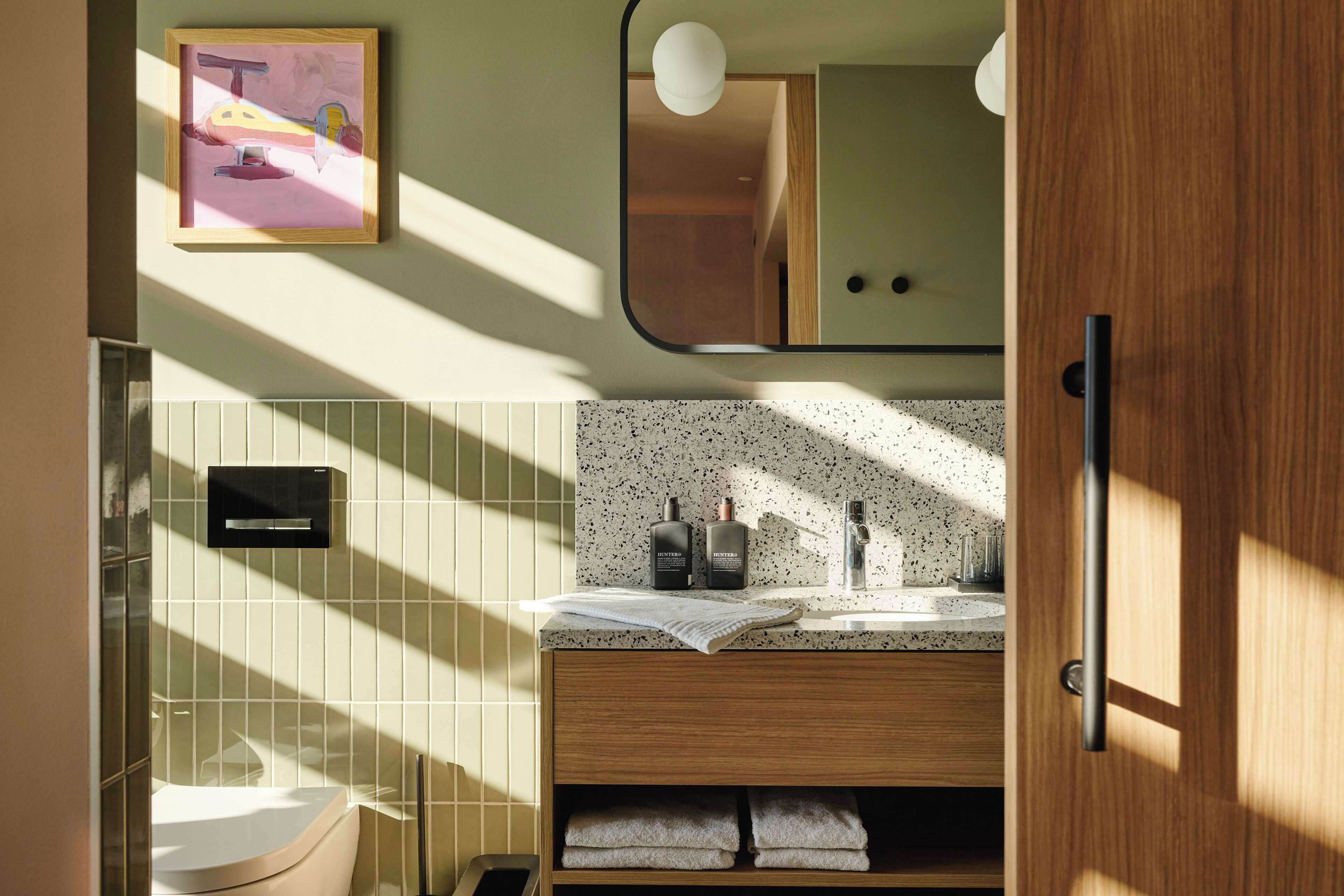 A modern bathroom with a wooden vanity, a sink with a speckled countertop, and a framed picture on the wall.