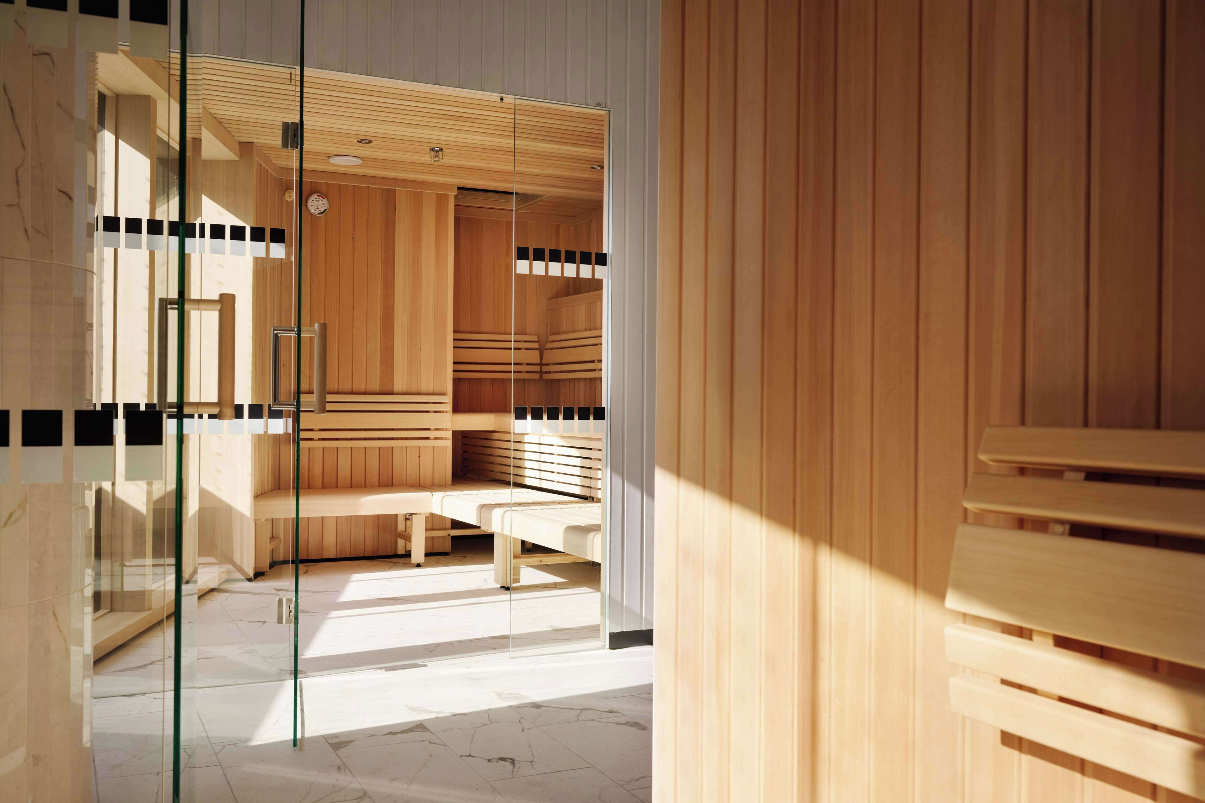 Un sauna avec des bancs en bois et une paroi en verre.