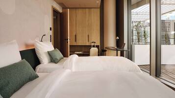 Habitación de hotel moderna con una cama grande, un armario de madera, una mesita con una lámpara y vistas al balcón exterior.