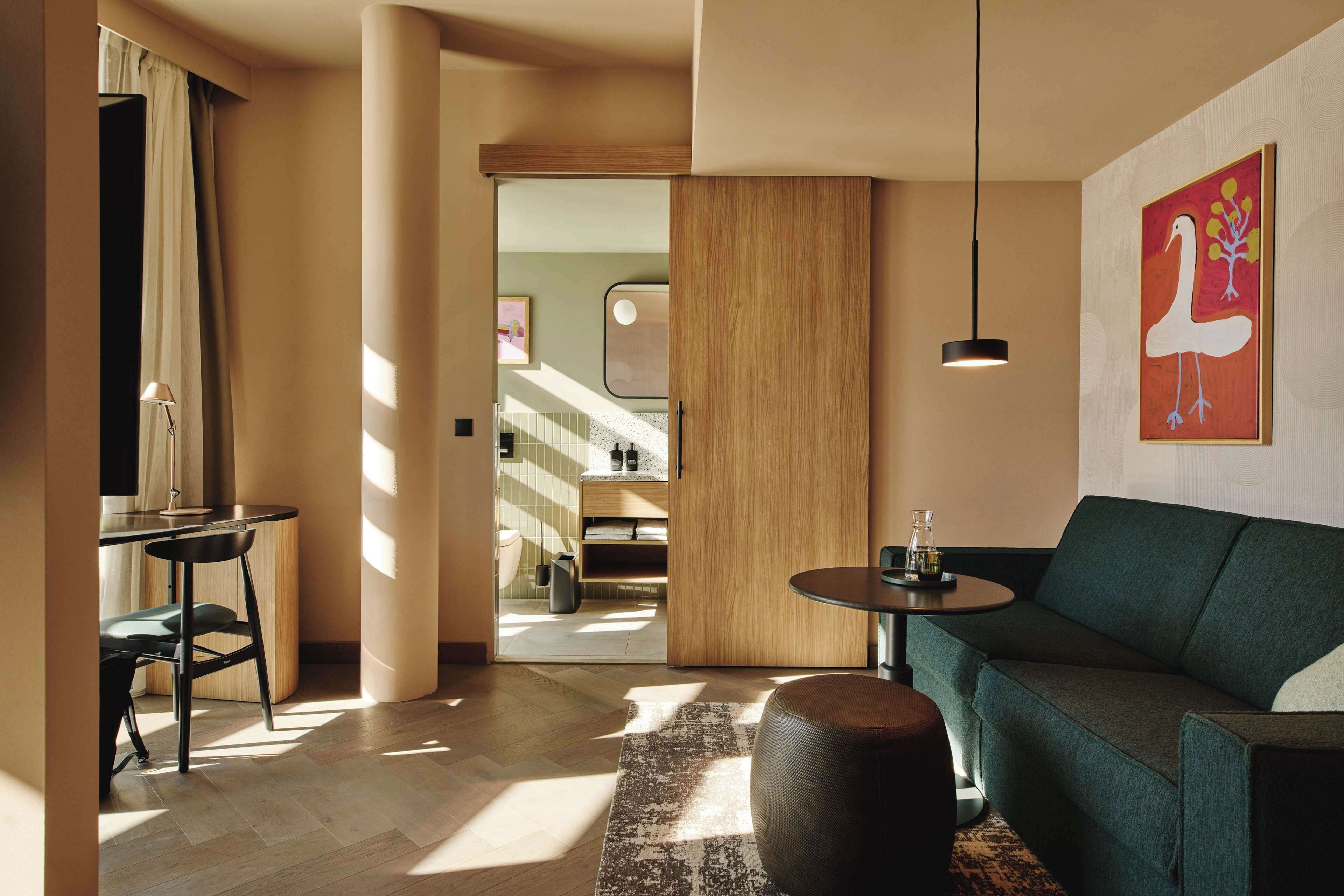 Ein modernes Wohnzimmer mit einem grünen Sofa, einem runden Couchtisch und einem gemusterten Teppich.