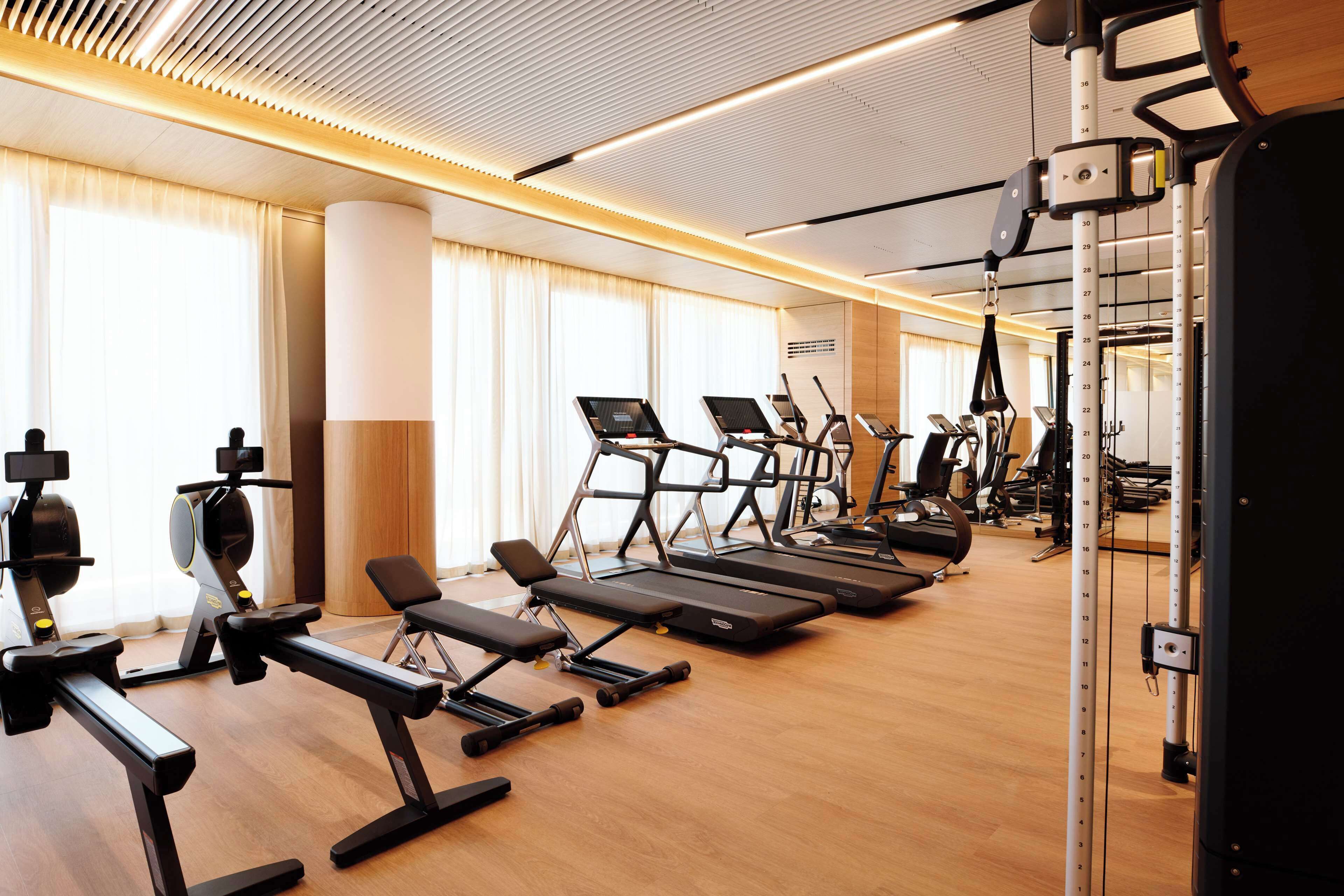 A gym with treadmills, elliptical machines, and weight benches.