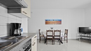 A modern kitchen with a gas stove, coffee maker, and a dining table with chairs.