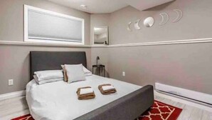 Une chambre à coucher avec un lit, des oreillers, une table de chevet, un miroir et un mur décoré de motifs en forme de lune.