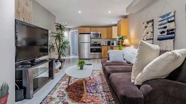 Un salon moderne avec un téléviseur à écran plat, un canapé, une table basse et une cuisine en arrière-plan.