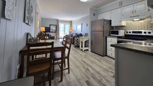 Une cuisine moderne avec des armoires blanches, un four encastré et un coin repas comprenant des chaises et une table en bois.