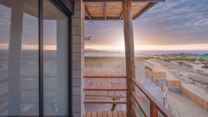 Un balcón con baranda de madera que da a una playa y un paisaje urbano.