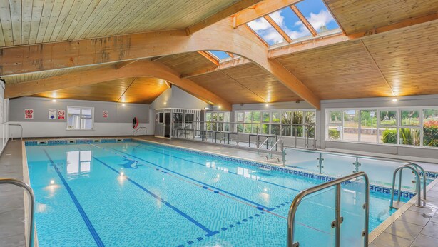 An indoor swimming pool with clear lanes, a wooden ceiling, and large windows. - 2 bedroom accommodation in Lowestoft (Lowestoft)
