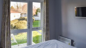 A bedroom with a large window, a bed, and a TV mounted on the wall. - 2 bedroom accommodation in Lowestoft (Lowestoft)