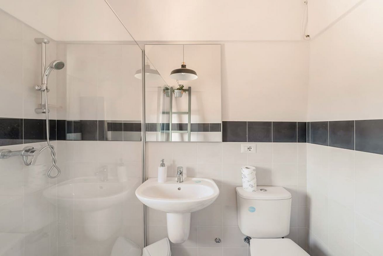 A modern bathroom with a glass-enclosed shower, a pedestal sink, and a toilet.