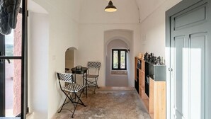 A narrow hallway with a table and chairs, a wooden cabinet, and a door. - Unity House Sleeps 4 with terrace - Masseria 1 by Rentbeat (Ceglie Messapica)