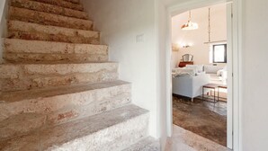 A staircase with stone steps leading to a modern living area with a sofa and a dining table. - Unity House Sleeps 4 with terrace - Masseria 1 by Rentbeat (Ceglie Messapica)