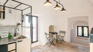 A modern kitchen with a built-in sink, a dining area with two chairs, and a pendant light fixture. - Unity House Sleeps 4 with terrace - Masseria 1 by Rentbeat (Ceglie Messapica)