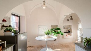 Una cocina moderna con una mesa redonda blanca, armarios blancos y diversas plantas.