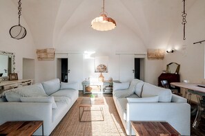 Un salon spacieux avec deux canapés bleu clair, une table basse en bois et un luminaire suspendu.