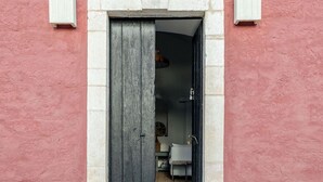 Una puerta que da a un cuarto con una silla blanca y una pequeña mesa.