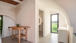Habitació àmplia amb una taula de fusta, una planta en test i una vista de l'exterior a través d'una porta gran.